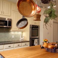 Country Kitchen With Off-White Cabinets and Metal Pot Rack