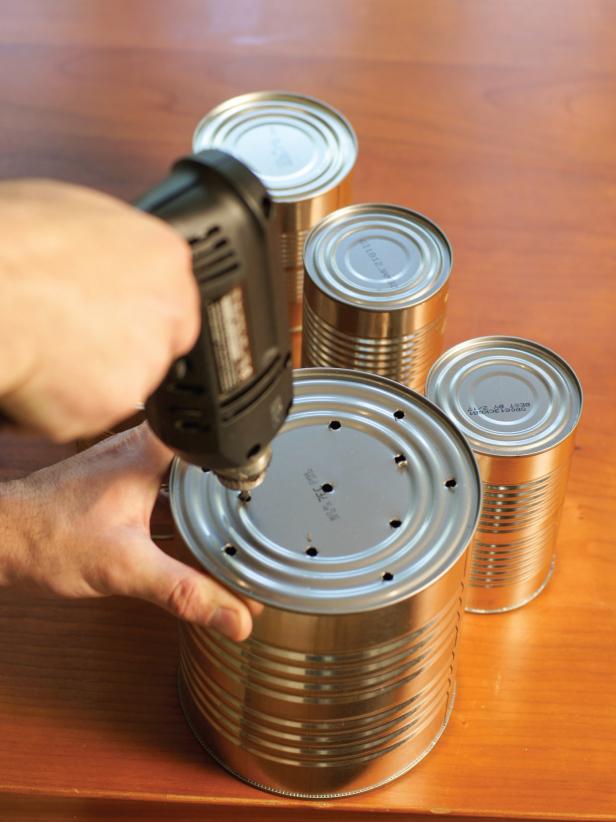 Set the smallest can aside (this will be used later to keep scissors for snipping the herbs handy), then flip the remaining five cans over and drill several, evenly-spaced holes in the bottom for drainage.