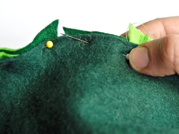 Sew triangles together with coordinating green thread. Remove pins. Pin sewn scales into slit in back of sweatshirt, leaving about a 1 inch gap. Sew along pin line. Remove Pins.