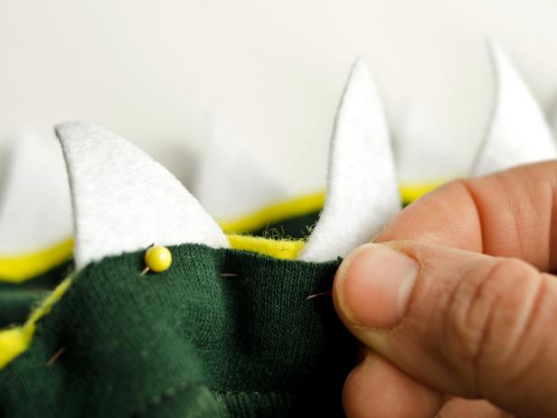 Secure teeth and gums by pinning them into place. Allow yellow strips to slightly overlap behind a tooth when one ends and another begins. Then, sew along pin line with green thread to secure teeth and gums in place
