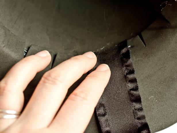 After cutting the black ribbon into two 20-inch lengths , Step 6C in making a witch's hat is to glue the ribbon's ends to inside of the witch's hat with beads of hot glue. Hold the ribbons in place until the glue cools.