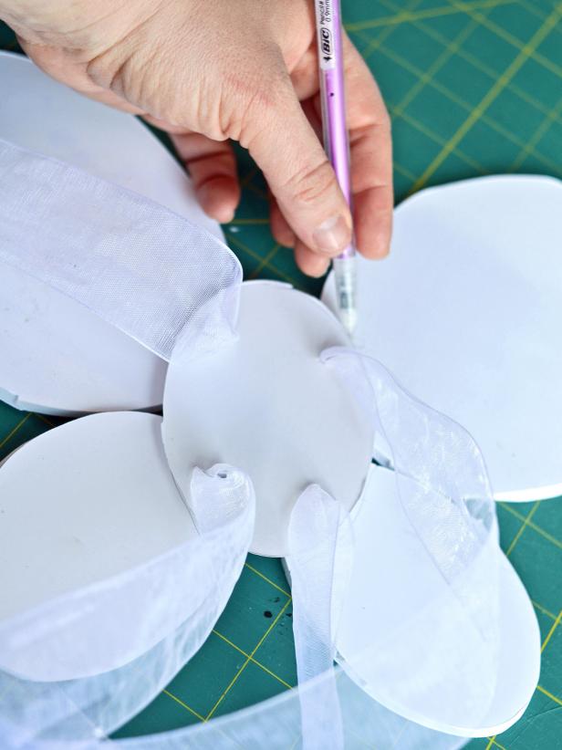 Step 3A is to place four ovals, with the large on top, on a work surface in a butterfly wing pattern. Place the oval with ribbon straps over the center of the other ovals and trace around its location with pencil.