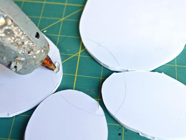 After tracing the oval with the ribbon strap over the center of the other arranged ovals, Step 3B in making feathered angel wings is to remove the ribbon strap oval. Apply hot glue inside the traced area.