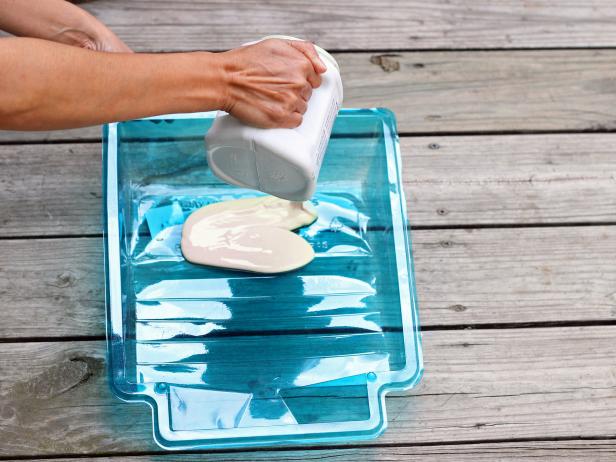 Step 2 in the process of crafting a bathroom caddy for guests is to gather paint and a pan for dipping the wooden box. Pour the paint into the pan.