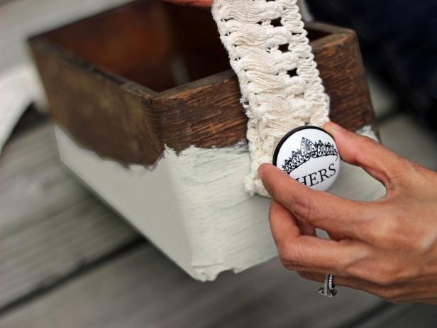 Step 5 in crafting the rustic bath caddy is to secure the doorknobs on the wooden box.Get the doorknobs ready and secure the fabric trim on each side of the box by inserting the front of the knobs into the drilled holes on each side. Fasten and secure the nuts and bolts to the box.