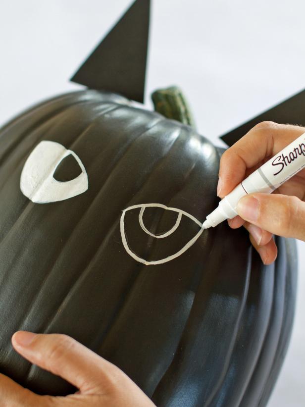 Use a white paint pen to draw on angled cat eyes then fill them in using the paint pen or a small paintbrush and white craft paint.