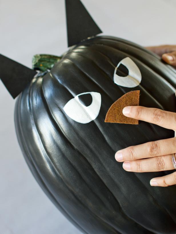 Apply a dab of hot glue to the center of the nose only and secure it to the pumpkin just below the eyes.