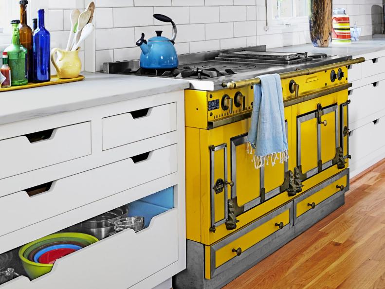 A yellow stove range with a white storage cabinet.  