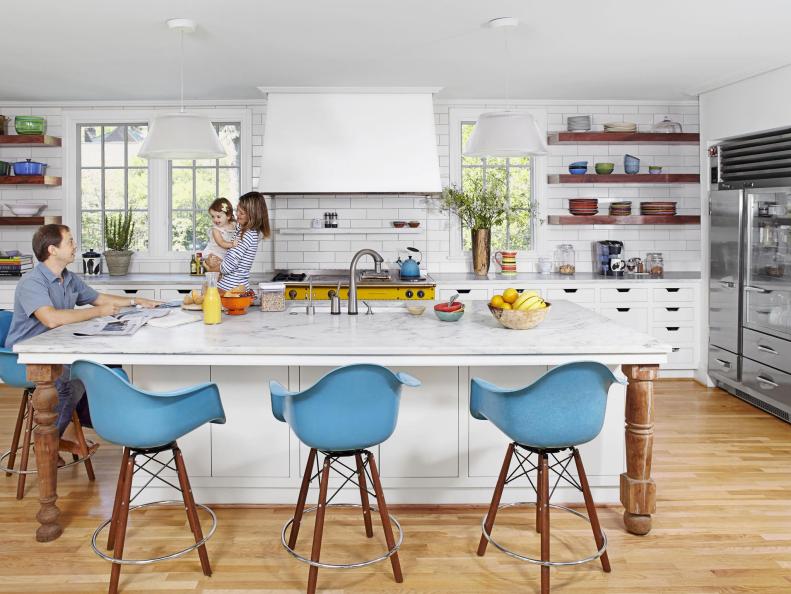 Blue bar stools surrounding a large white table in the kitchen. 