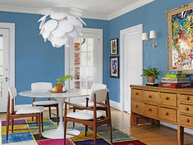 Dining room with electric blue walls and a white chandelier. 