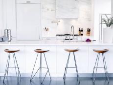 White Kitchen With Marble Backsplash, White Countertops & Wood Stools