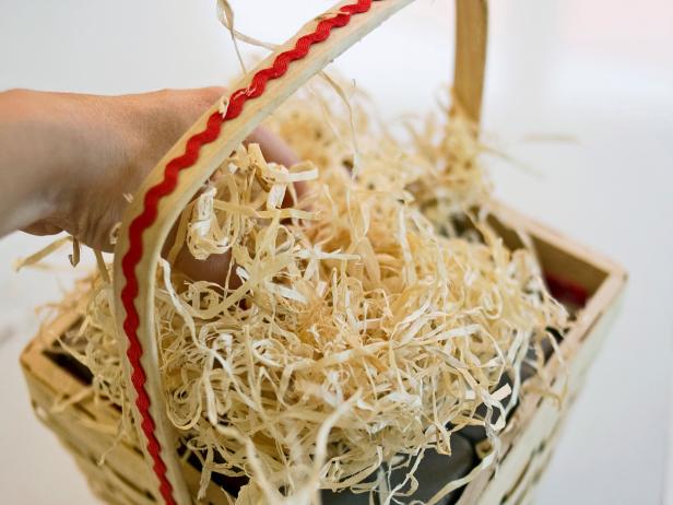 Person topping decorative basket with shredded filler