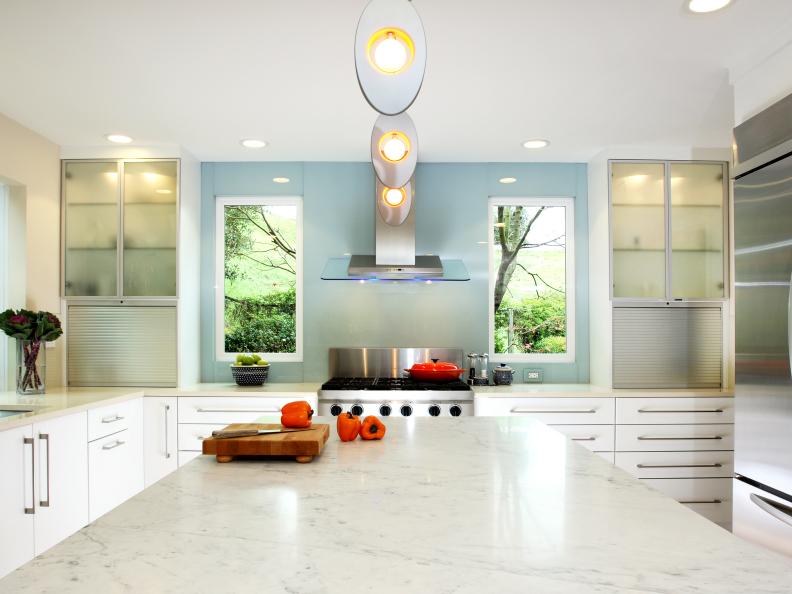 White Kitchen With Large Island and Modern Lighting