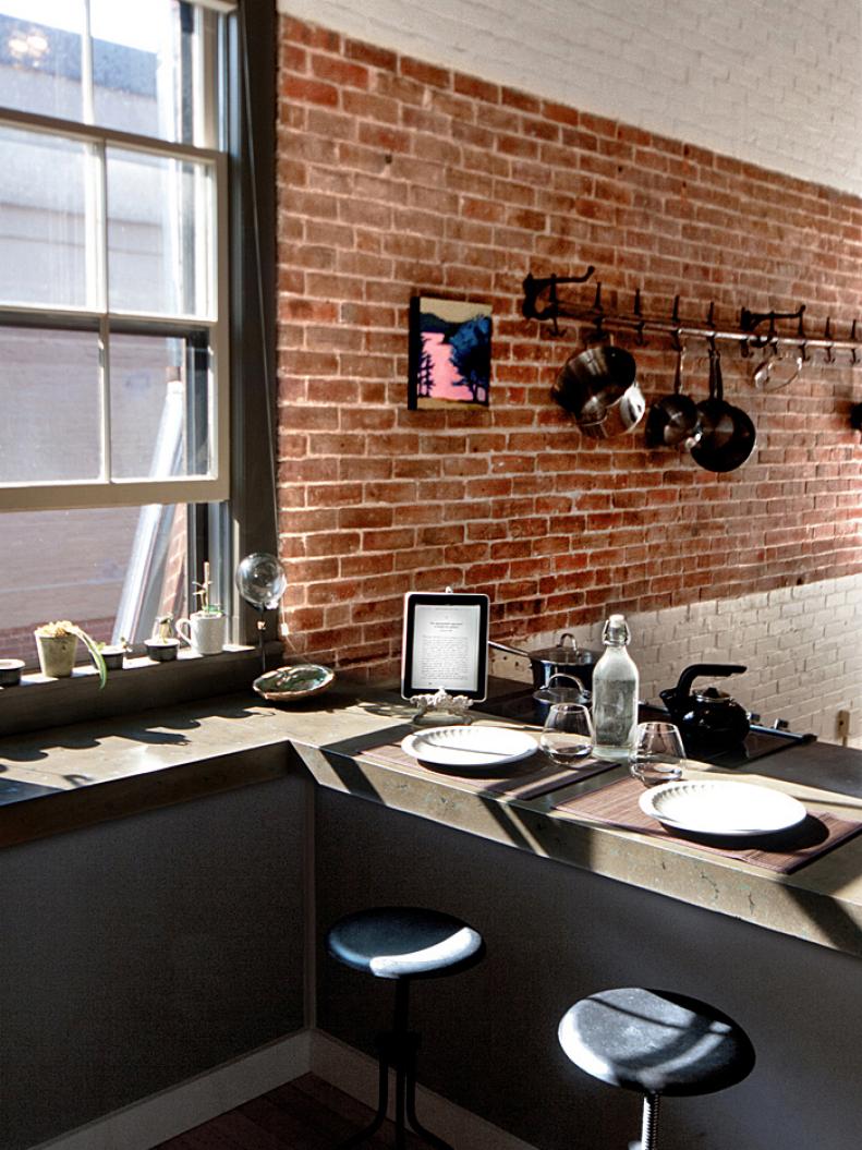 Pots and pans hung on exposed brick wall. 