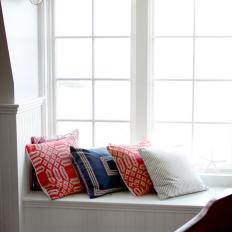 White Window Seat With Red and Blue Pillows