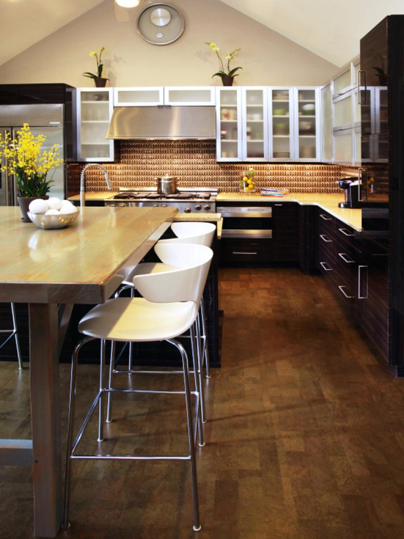 Wood countertops in a subtle tone are selected for the island. The glossy finish of the countertops keep with the contemporary style of the kitchen and are paired with sleek white barstools.