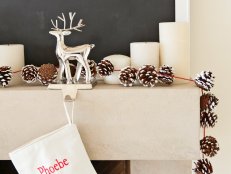 Mantel Decorated With Pinecone Garland and Reindeer Stocking Holder