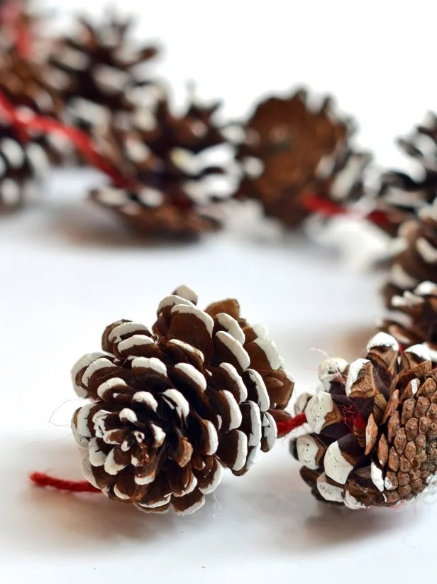Continue wrapping yarn around pinecones, wedging yarn under scales to secure it. Once desired length is reached, cut yarn.