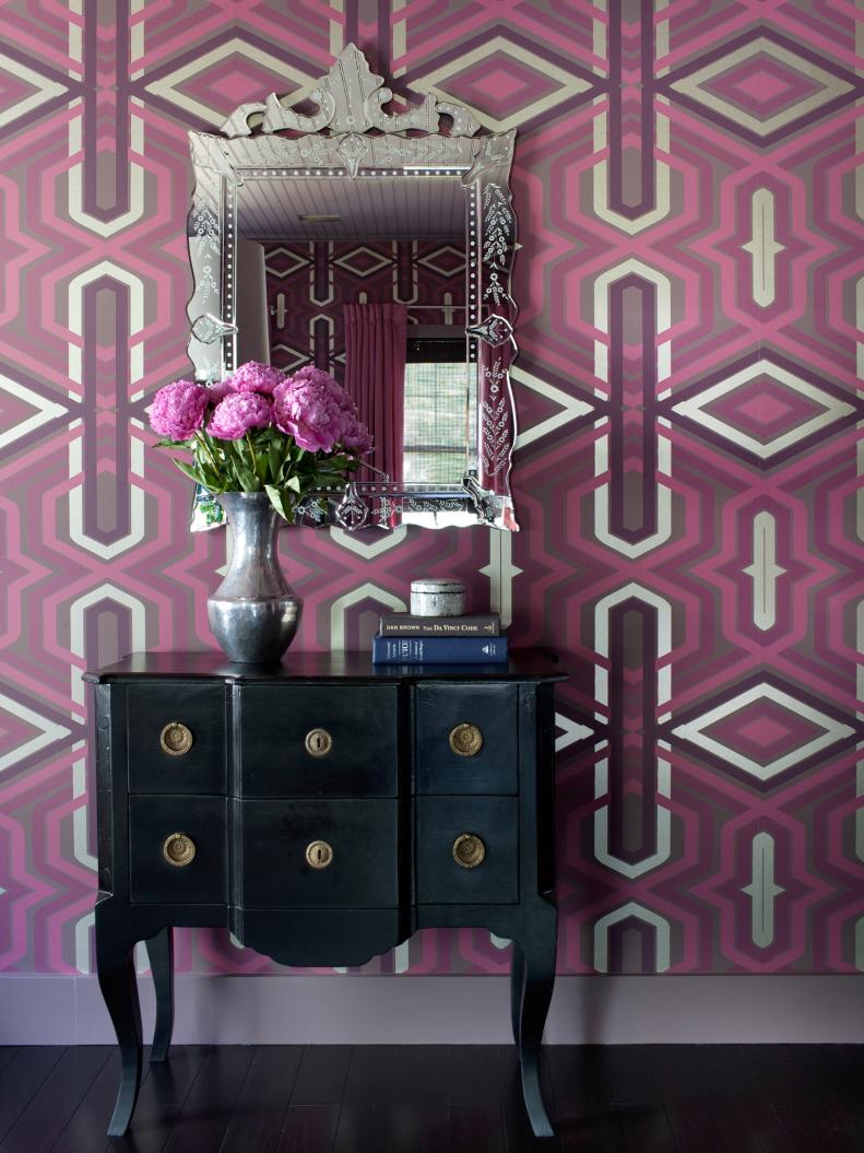 Black Dresser and Ornate Mirror Against Plum & Fuchsia Patterned Wall