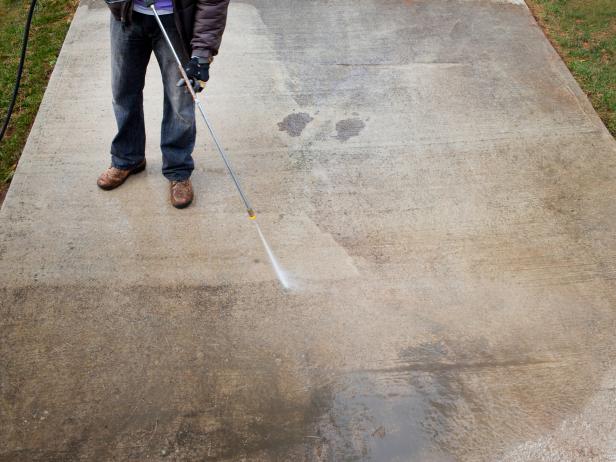 Pressure wash concrete by holding down spray handle, working your way back and forth from one side of concrete to the other, making clean and distinctive lines.