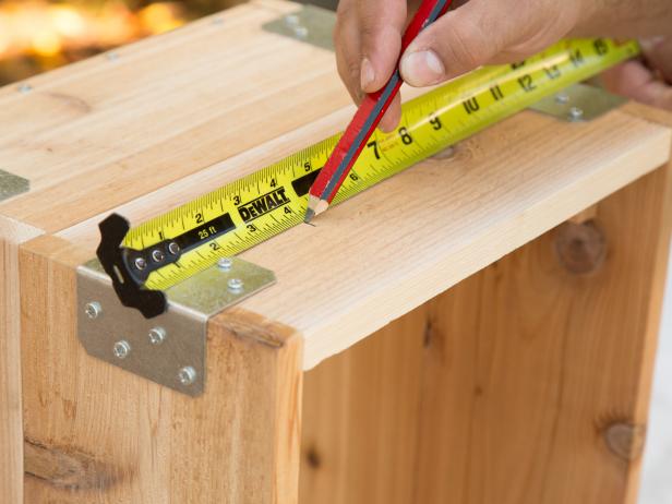 Measuring and Marking Spot on Wood Crate With Tape Measure and Pencil