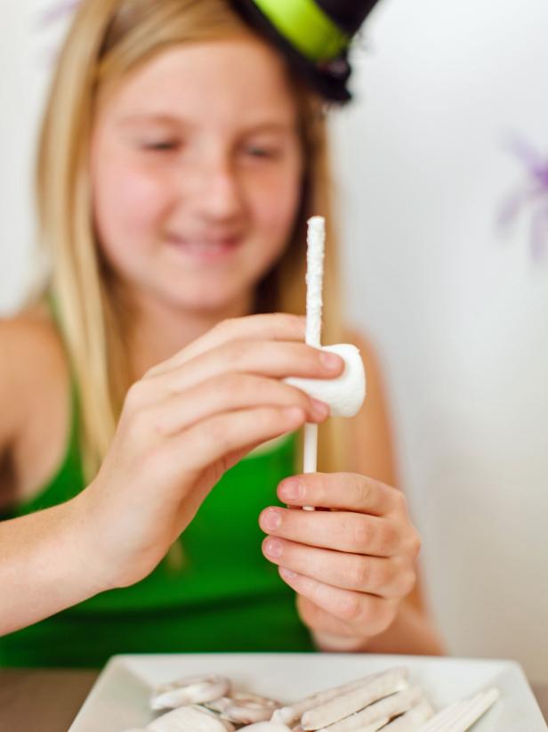 Begin to build the skeleton by sliding a large marshmallow about halfway down a lollipop stick.