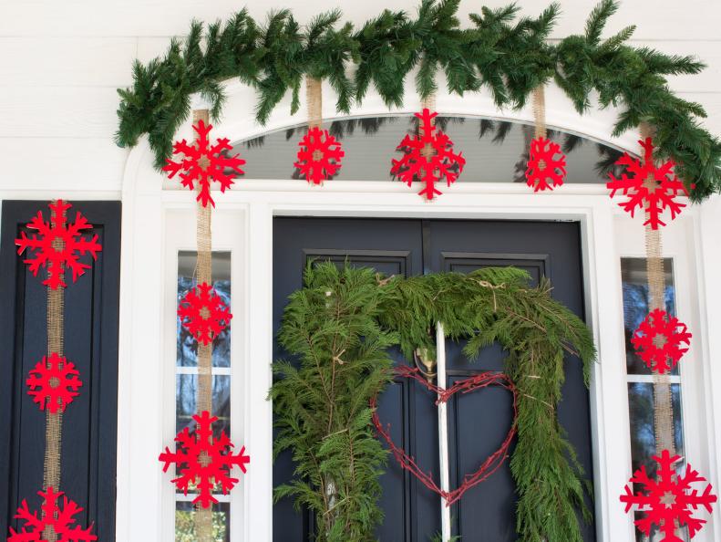 Pine sprigs darker than the square wreath help to drastically frame the arched window above the door.