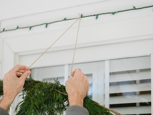 After all ornaments are securely fastened to tree-hanging bunch, use hammer to add a small nail above the window. Place twine hanger on nail. Stand back to adjust hanging until it's perfectly straight.