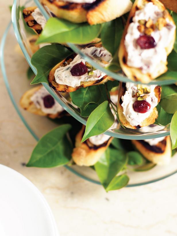 Spread cream cheese mixture onto toasted baguette slices. Garnish with cranberry pieces and sprinkling of pistachios.