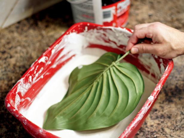 Dip each large leaf fully into the wet plaster. Gently shake off excess and clip the leaves onto a hanger with the points facing down. Pull the sides slightly together to create a bit of a fold in the leaf and allow leaves to dry. Prevent remaining wet plaster from drying out by covering with plastic wrap.