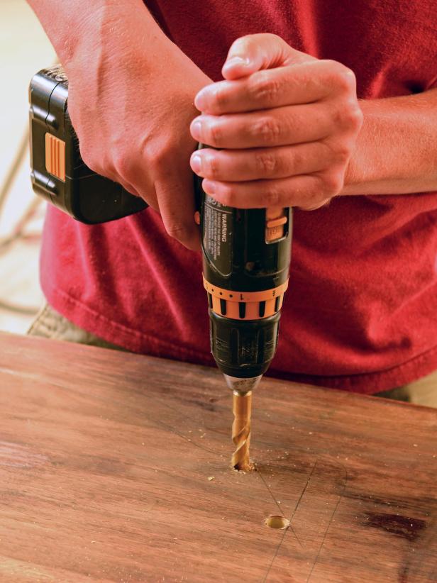 A vintage dresser's top is drilled to prepare to cut a sink-sized hole.