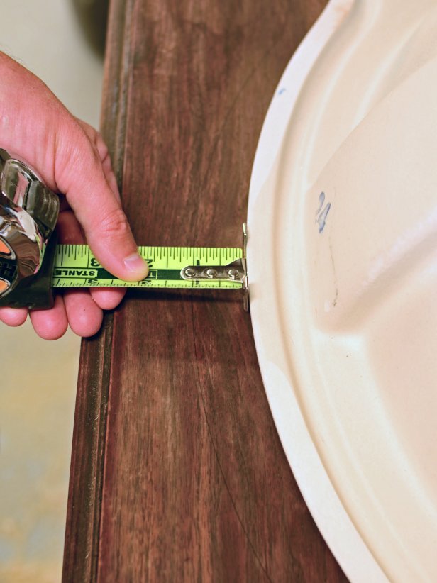 The area for a sink installation is measured on a vintage dresser.