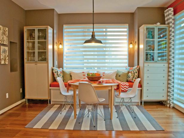 Eclectic Dining Room with neutral walls, a gray and white rug and orange accents.