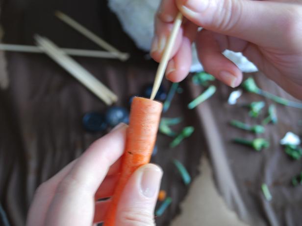 Snap or cut carrot down to four inches in length, then insert six-inch skewer into carrot. Place carrot into center of top sphere for use as a nose.