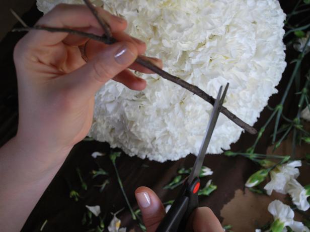 Cut twigs to approximately eight inches in length with scissors, then insert them into each side of the center sphere for use as arms.