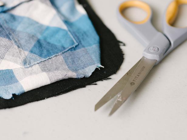 Cut a solid contrasting linen or cotton duck fabric roughly 3 inches longer than the length of the shirt pockets using fabric scissors. Note: The additional inches along the top will account for a flap which will fold along the back, creating a pocket for the 3/4-inch canvas banding to string the pennants together.