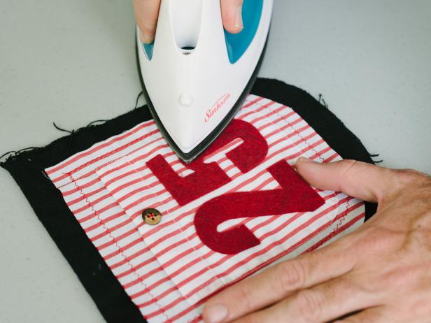Trace numbers to felt using stencil as a guide. Next cut numbers out using fabric scissors. Once each number is cut out, attach to the front of a pocket using iron-on adhesive tape.