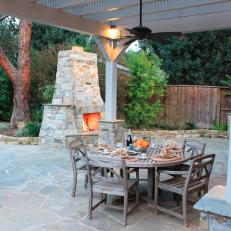 Mediterranean Outdoor Dining Area With Stone Fireplace