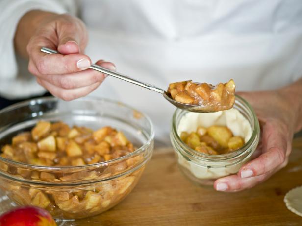 Spoon apple pie filling into dough-lined Mason jar.