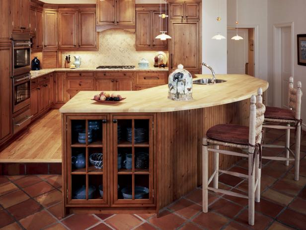 Knotty-pine cabinetry matches existing cabinets throughout this friendly, family home. Warm tones make this room a great entertaining space. Note the step up to the working area from the bar area.