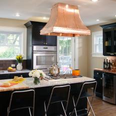 Kitchen With Black Cabinetry and Copper Range Hood