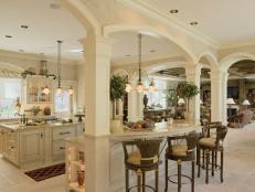 Designed to evoke the French Colonial period,and a two-tiered Madura Gold granite island features a wet bar and two integrated white ovens. The island also features a raised seating area perfect for gatherings.
