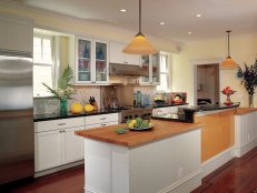 In this appealing kitchen, the designer limited the use of the most expensive materials and employed simple bilateral symmetry to create a fresh and workable room. By putting glass fronts on two of the upper cabinets, he maximizes both light and space. (Design by Andre Rothblatt)