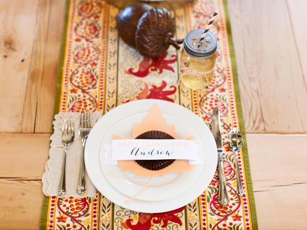 Colorful autumn decor brightens up this rustic wooden table for Thanksgiving. A homemade place setting in the shape of a leaf is a nice personal touch.