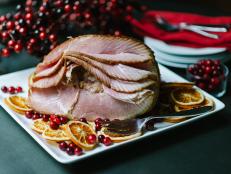 Sliced Holiday Ham on White Plate With Oranges and Berries