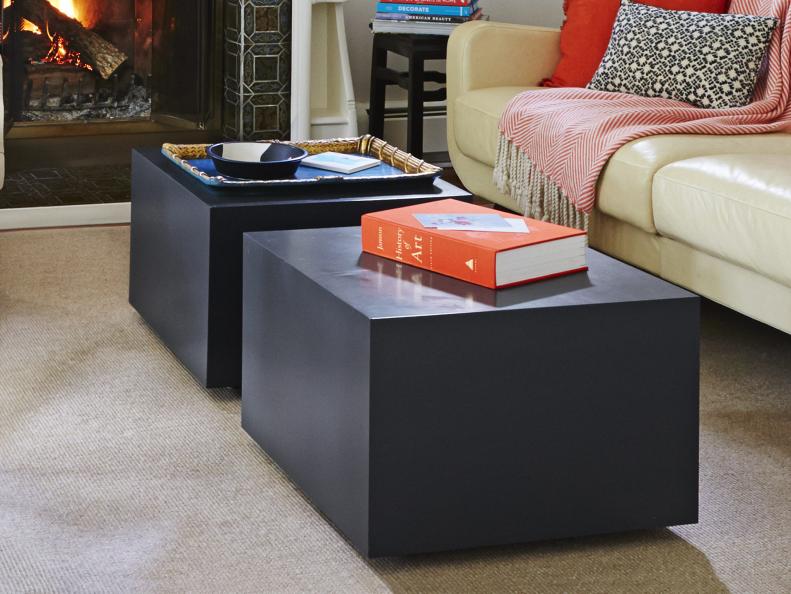Coffee table made from two black cubes, in front of sofa. 