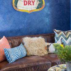 Textured Blue Living Area With Brown Leather Sofa and Vintage Metal Sign