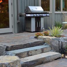 Stone Patio With Grill and Minimal Landscaping