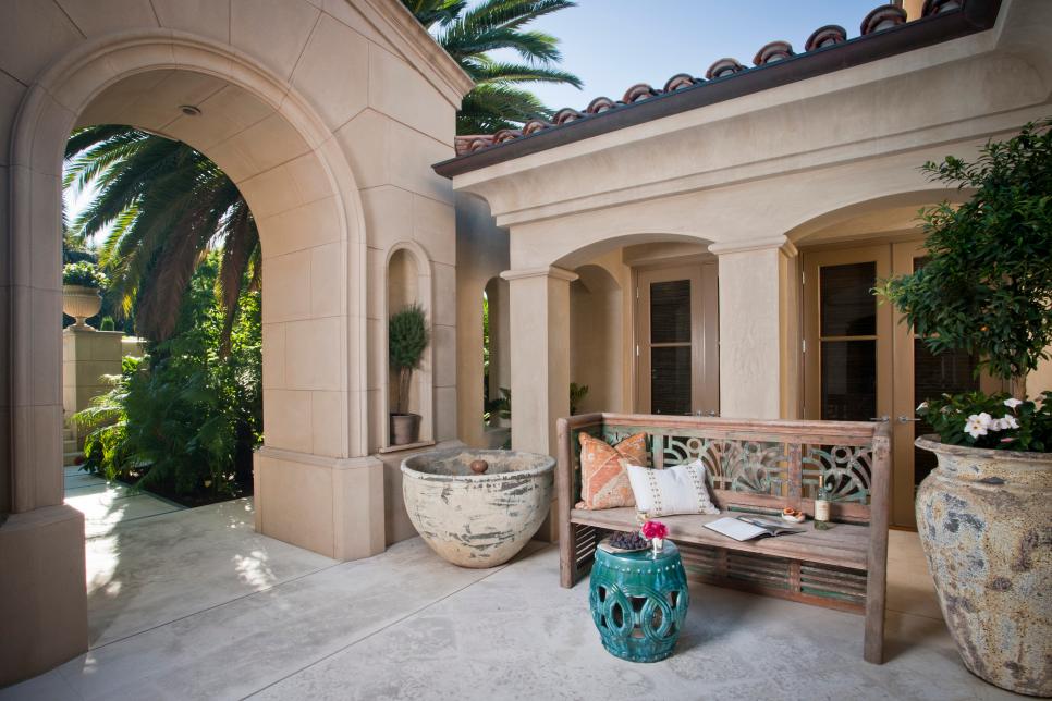 Mediterranean Courtyard With Large Arched Entryway and Wood Bench
