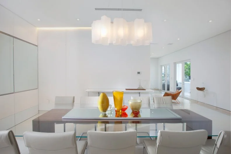 Glass-topped dining table "floats" in an all-white dining room